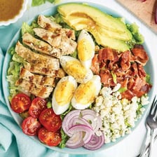 A Cobb salad arranged with bacon, blue cheese, eggs, and other toppings.