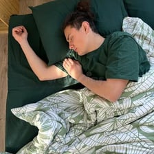 A sleeping person in a peaceful outdoor setting with a log nearby