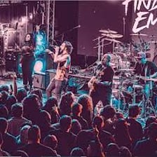 A rock band performing in an emo-style concert setting.