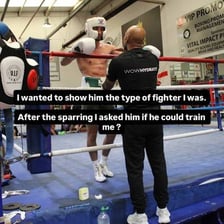 A boxing trainer practicing punches with an athlete wearing gloves.