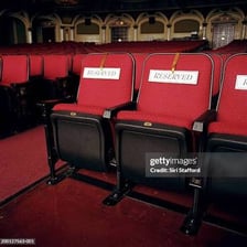 An empty seat in a theater with surrounding occupied seats