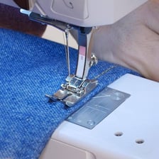 A tailor shortening the bottom of a pair of jeans.
