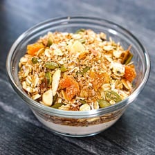 A bowl of muesli containing visible oats, nuts, and dried fruit.
