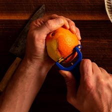 A person removing the peel from an orange