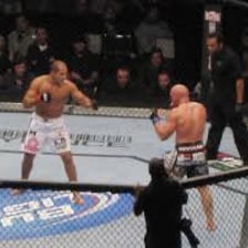 Two athletes competing in a mixed martial arts cage.