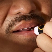 A person applying lip balm to their lips.