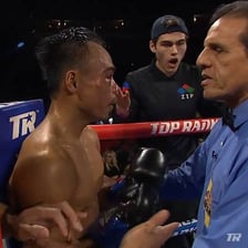 A boxing referee signals the end of a match.