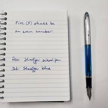 A pen using ink to write in a notebook