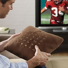 A television remote control resting among couch cushions