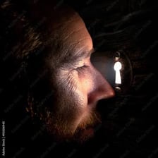 A person looking through a keyhole from the other side of a door