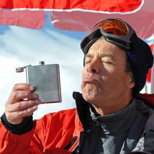 A person taking a drink from a flask.