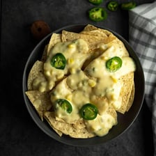 A platter of tortilla chips topped with melted cheese and other nacho toppings.