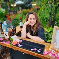 A bartender working at a bar beside a gardener caring for plants