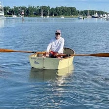 A rower uses a long oar to move a boat through the water.