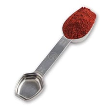 A teaspoon measuring spoon filled with a cooking spice