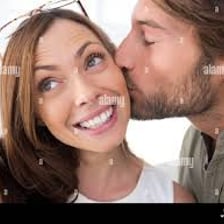 One person giving another person a kiss on the cheek