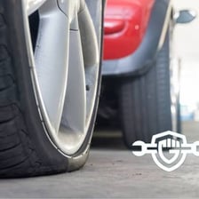 A car tire visibly flattened from low air pressure.