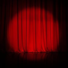 A theater stage framed by curtains and lit by spotlights