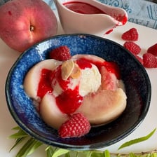 Peach Melba served with peaches, vanilla ice cream, and raspberry sauce.