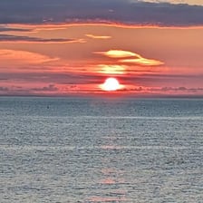 The sun rising over a horizon