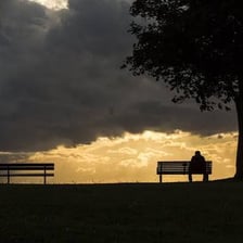 A person sitting alone on a bench.