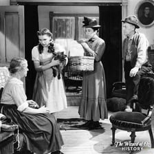Dorothy standing with Toto in a scene from The Wizard of Oz.