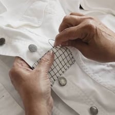 Person using needle and thread to mend torn fabric