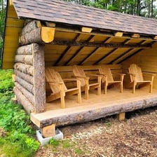 A simple lean-to shelter made from branches in a wooded area