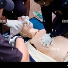 A paramedic practicing CPR on a training mannequin.