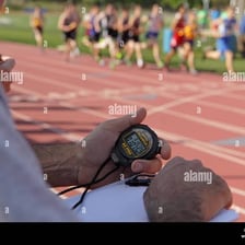 An athlete runs around a track while a coach gives instructions.