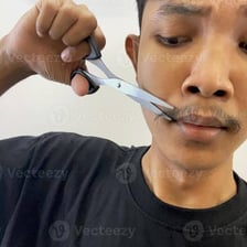 A man shaping his beard with grooming scissors.