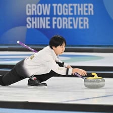 A curling player sliding a stone across the ice.
