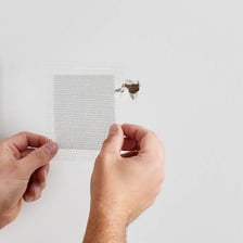 Person applying spackle to a hole in a drywall wall