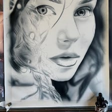 An artist using an airbrush to apply a fine spray of paint