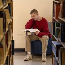 A scholar reading books in a university library.