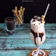 A thick vanilla milkshake served in a tall glass.