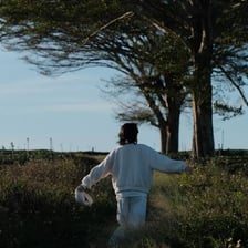 A person walking without a clear destination across an open landscape.