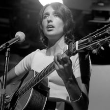Joan Báez performing as a folk singer with an acoustic guitar