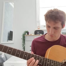 A musician casually experimenting with notes on a guitar.