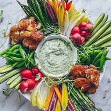 A platter of sliced raw vegetables served with dipping sauce