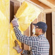 Rectangular fiberglass insulation batts fitted between wall studs