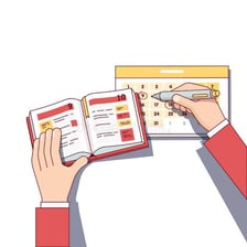 A person writing an appointment into a paper diary.