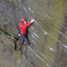 A climber navigating a steep rock face while managing the risks of the activity.
