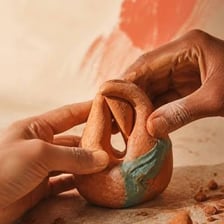 Hands changing the shape of a piece of clay.