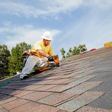Roofers installing shingles on the top of a house