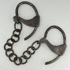 A person's wrists secured with metal manacles.