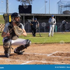 A baseball catcher crouched behind home plate receiving a pitch