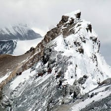 A person carefully crossing a hazardous mountain ridge.