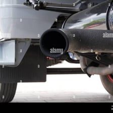 A car’s tailpipe extending from beneath the rear of the vehicle.