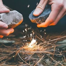 A match igniting a small pile of kindling